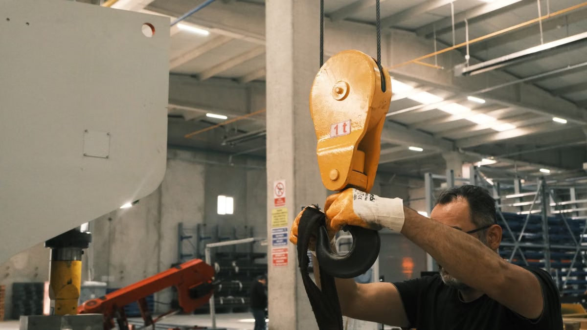A worker operates industrial lifting machinery in a Konya factory setting.